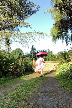 In an outfit with a pink nightgown and a sheer white dressing gown with a parasol