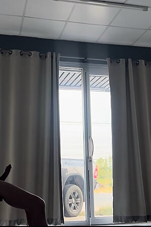 A handsome young man jerks off in front of a glass door.